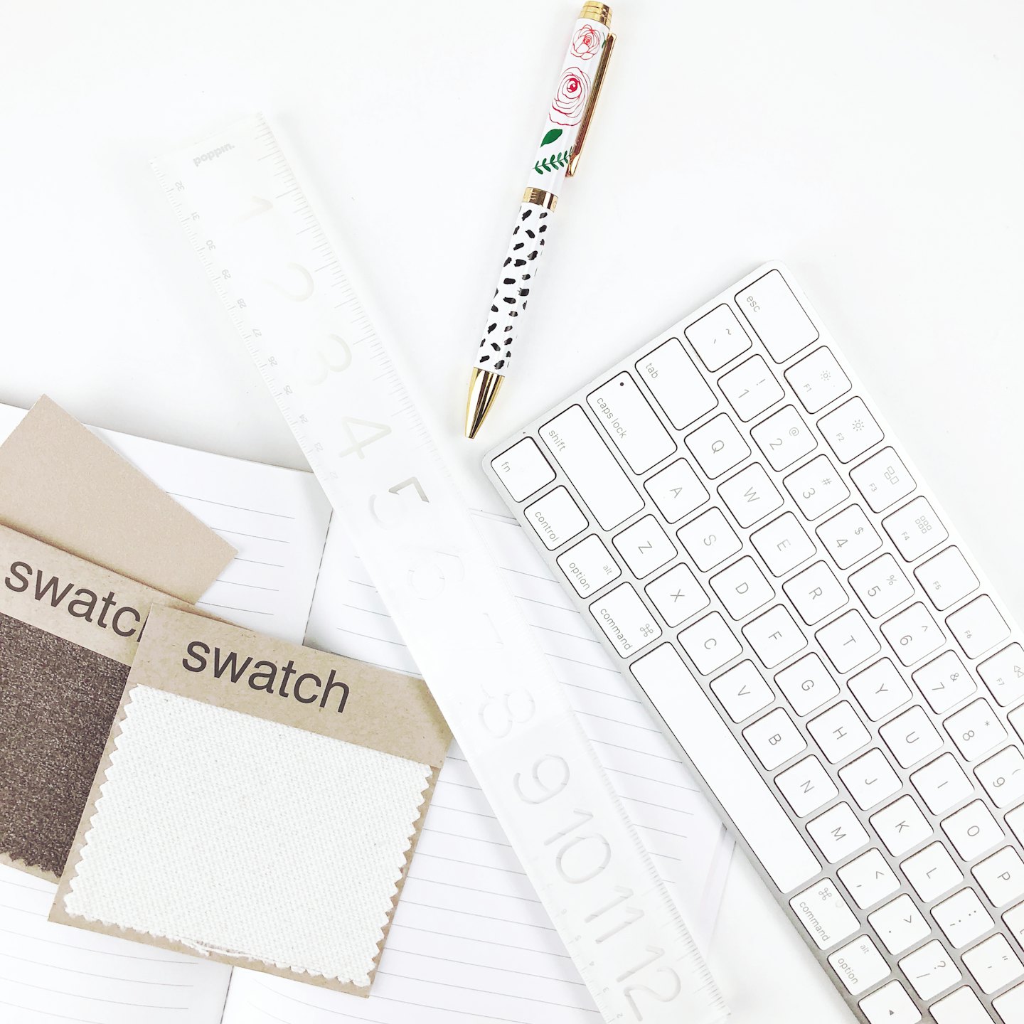 Flat lay of office supplies and fabric swatches on a white desk.