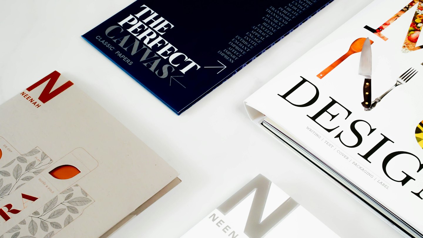 Printed marketing materials and paper samples laid out on a white surface.